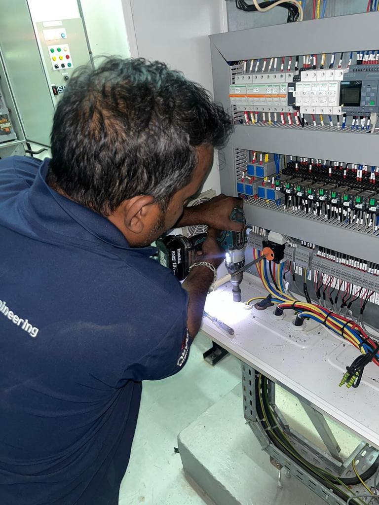 Auburn technician wiring breakers inside a live control panel