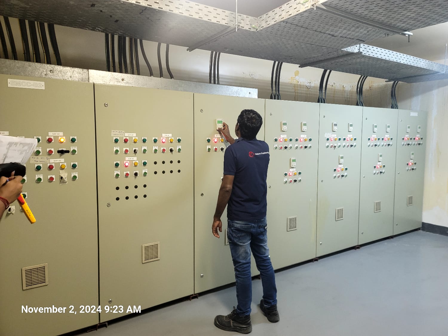 A technician operates one of a row of MCC panels — facility-scale electrical control.